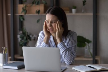 İş yerinde baş ağrısı çeken sağlıksız genç bir iş kadını..