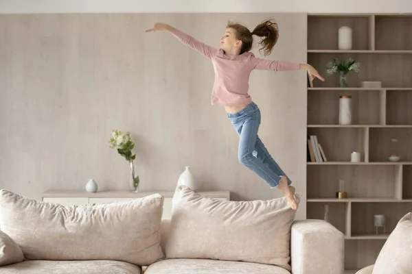 Bonito menina criança se divertindo, pulando alto no sofá — Fotografia de Stock
