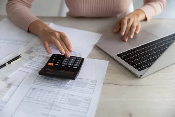 Gros plan femme calcul des factures, à l'aide d'une calculatrice et ordinateur portable — Photo