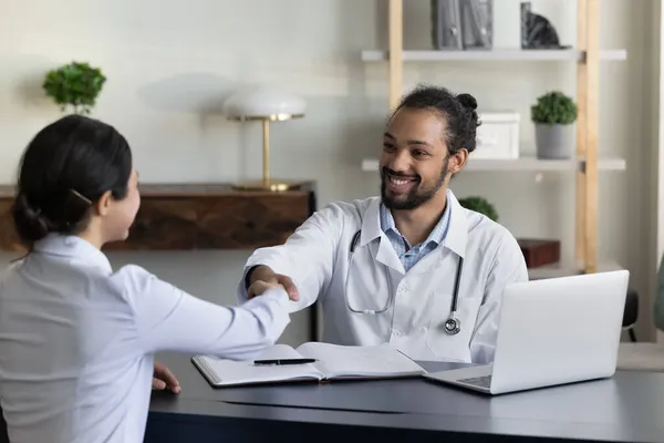 Sonriente médico afroamericano y cliente indio paciente estrechando la mano —  Fotos de Stock