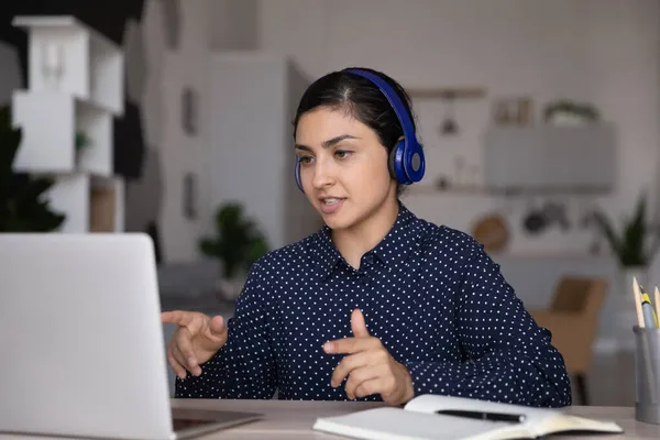 Concentrated young Indian businesswoman in headphones holding videocall. — Stock Photo, Image