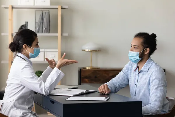 Indian woman doctor in medical mask consulting African American patient — Stock Photo, Image