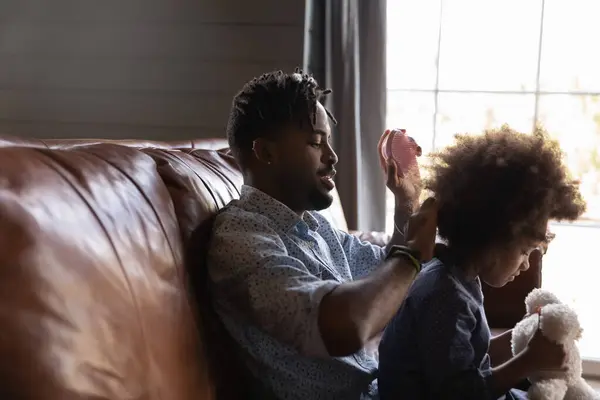 Heureux père africain peigner les cheveux de la petite fille. — Photo