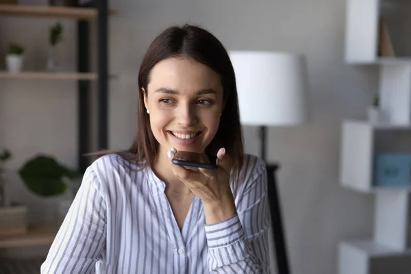 Smiling young woman sending voicemail or holding loudspeaker conversation. — Stock Photo, Image