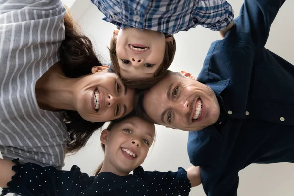 Visão inferior enfrenta família com crianças sorrir olhando para a câmera — Fotografia de Stock