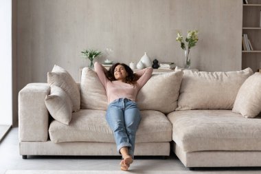 Evdeki rahat kanepede dinlenen yalınayak gülümseyen kadın.