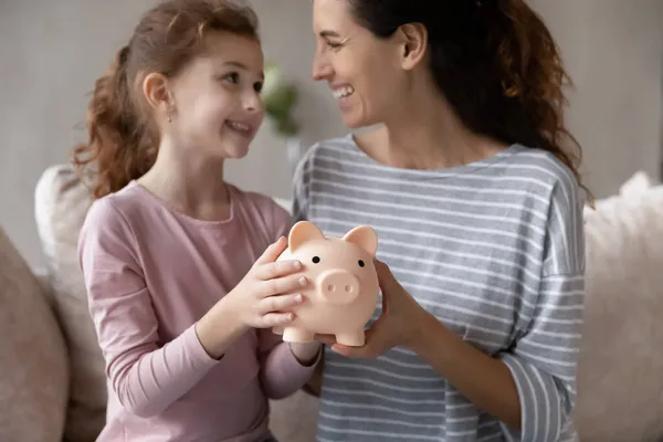 Nahaufnahme glückliche Mutter mit kleiner Tochter hält Sparschwein — Stockfoto