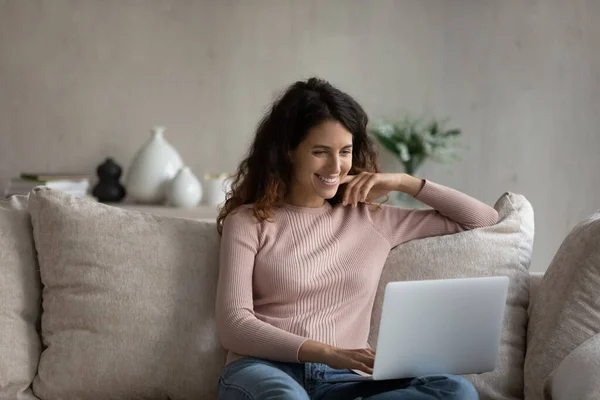 Mujer sonriente con portátil en el ordenador portátil sentado en el sofá —  Fotos de Stock