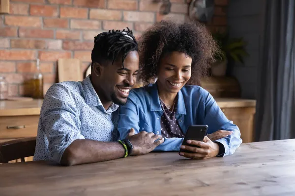 Gelukkig jong Afro-Amerikaans paar met behulp van mobiele telefoon. — Stockfoto