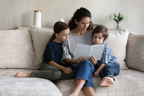 Vårdande mor läser fascinerande bok till små barn — Stockfoto