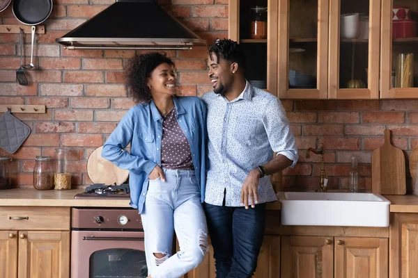 Glückliches junges afroamerikanisches Familienpaar spricht in Küche. — Stockfoto