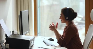 Kulaklık takmış genç Hintli kadın web konferansında fikir sundu
