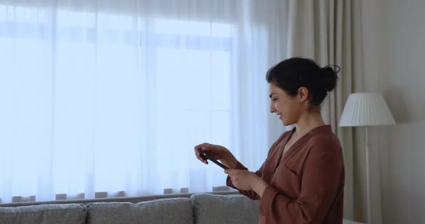 Ινδική θηλυκή σκιά κάτω από το παράθυρο χρησιμοποιώντας έξυπνο τηλέφωνο σπίτι app — Αρχείο Βίντεο