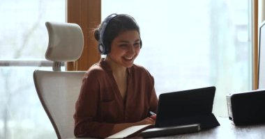 Genç Hintli kadın kulaklık takıyor. Laptop kullanarak uzaktan kumanda dersi alıyor.