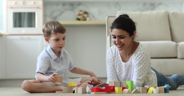 Indiase moeder kleine Kaukasische zoon spelen met blokjes op de vloer — Stockvideo