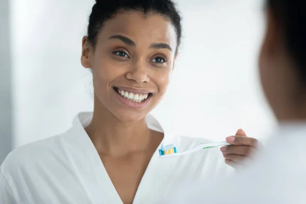 Genç Afrikalı Amerikalı kadın diş fırçasını macunla tutuyordu.. — Stok fotoğraf
