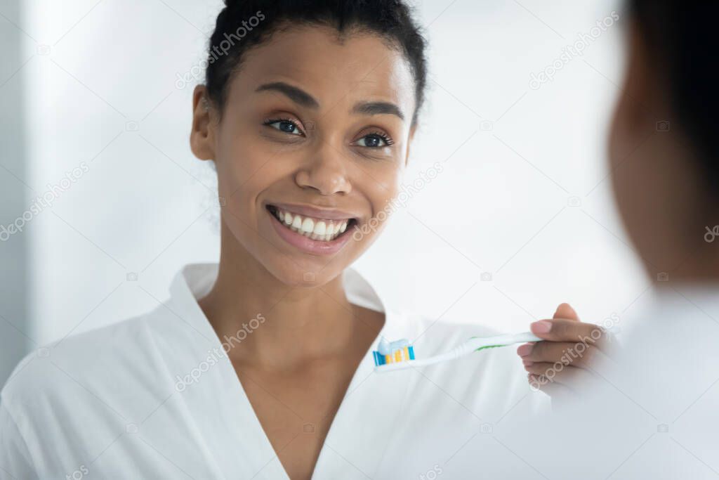 Young african american woman holding toothbrush with paste.