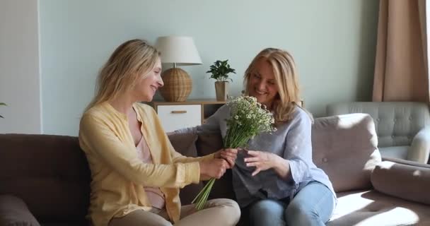 Omtenksom datter gir vårblomster til eldre mor – stockvideo