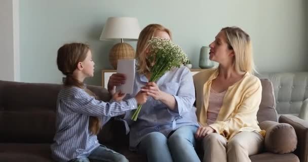 Glimlachende moeder kind geven maart 8 cadeau bloemen naar oma — Stockvideo