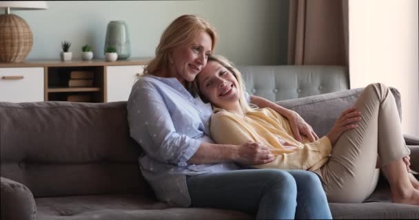 爱成熟的妈妈坐在沙发上拥抱爱抚成年女儿 — 图库视频影像