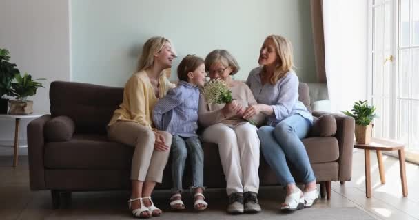 3 vrouwen familieleden dynastie geven kaart bloemen aan senior grootmoeder — Stockvideo