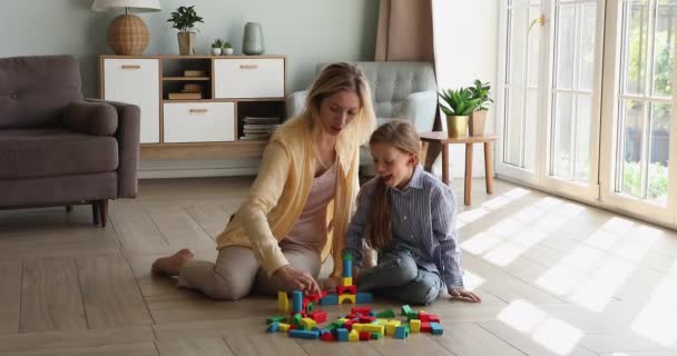 Jovem mãe pequena filha brincar com construtor na sala de estar — Vídeo de Stock