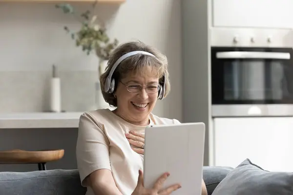 Alegre mujer mayor riendo en voz alta, utilizando tableta digital — Foto de Stock