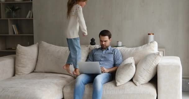 Apa dolgozni próbál, miközben csintalan kislány ugrik a közelbe. — Stock videók