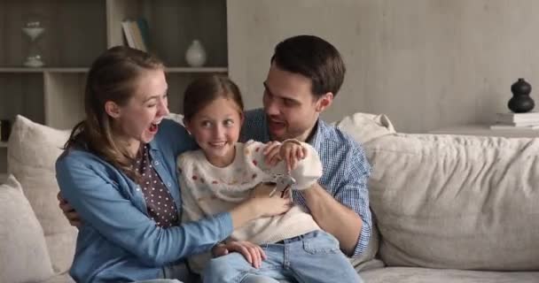 Kleines Mädchen kuschelt mit Eltern, die Schlüssel aus neuer Wohnung halten — Stockvideo