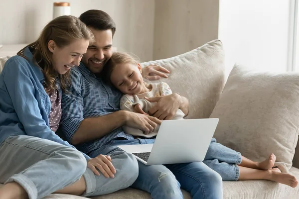 Glad familj tittar på rolig film på datorn med liten dotter. — Stockfoto