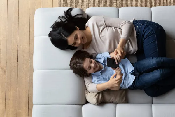 Femme et fils couchés sur un canapé avec smartphone, vue ci-dessus — Photo