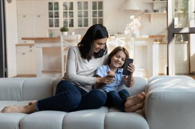 Neşeli anne ve oğul koltukta otururlar cep telefonuyla