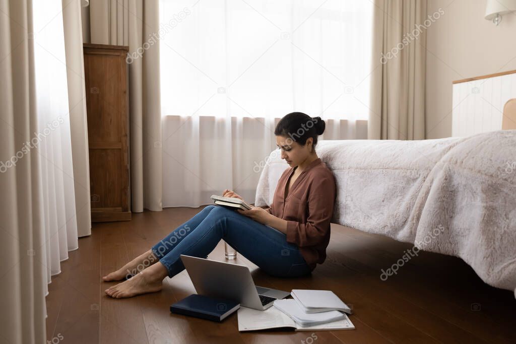 Happy young indian woman studying, sitting on floor.