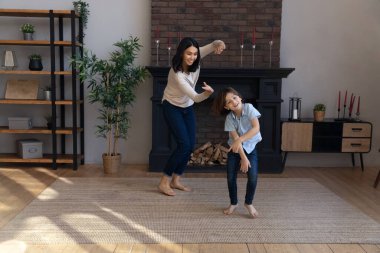 Aktif Asyalı bebek bakıcısı ve oturma odasında dans eden küçük çocuk.