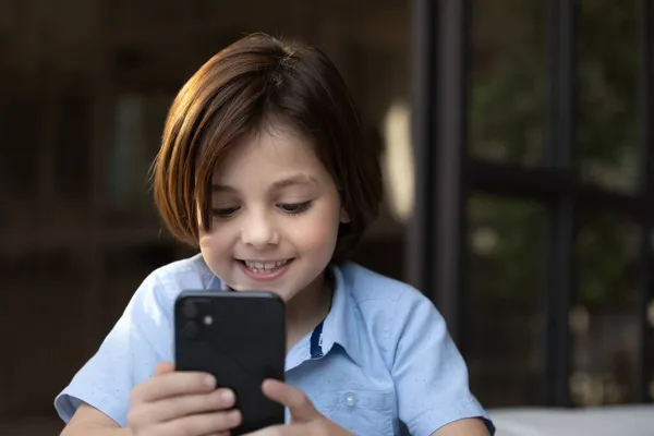 Boy looks at cellphone screen play videogame or having videocall — Stock Photo, Image