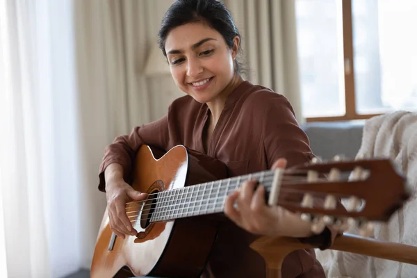 Улыбающаяся индианка, играющая дома на гитаре. — стоковое фото