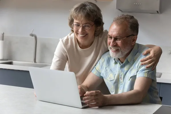 Boldog öreg pár használja laptop a konyhában, hogy videohívás — Stock Fotó