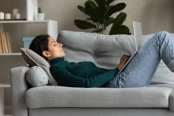 Latynoska freelancer leżąca na kanapie, pisząca na przenośnym laptopie — Zdjęcie stockowe