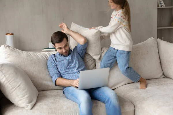 Ung far arbetar på datorn, medan barnet vill ha uppmärksamhet. — Stockfoto