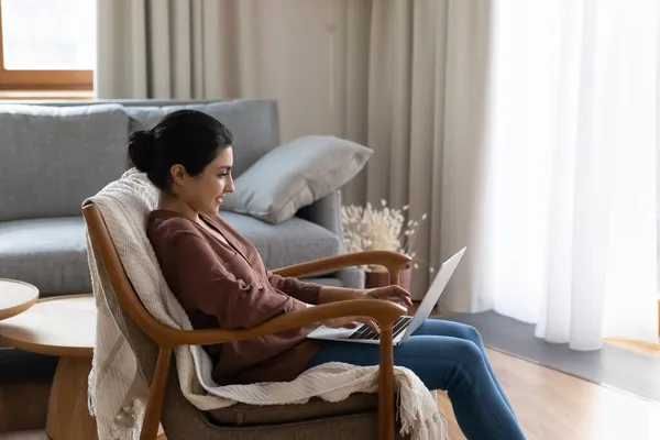 Sırıtkan Hintli kadın bilgisayar kullanıyor, koltukta dinleniyor.. — Stok fotoğraf