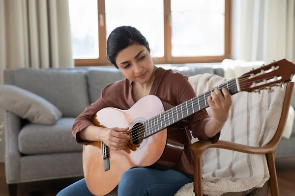 Glückliche junge indische Frau spielt zu Hause Gitarre. — Stockfoto