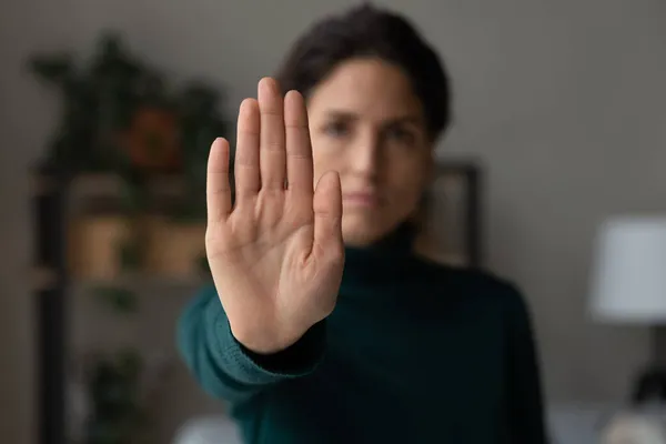 Strong young lady extending hand saying no to harassment abuse