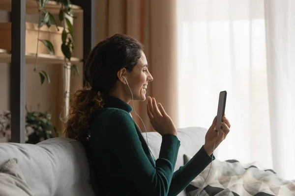 Ung latinamerikansk kvinna i headset njuta av videokonversation via telefon — Stockfoto
