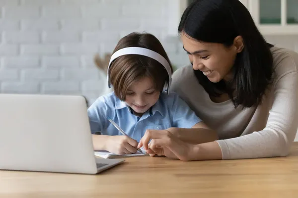 Asiatisk lärare hjälper till med läxor till liten skolpojke — Stockfoto