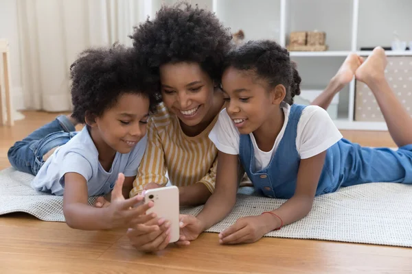 Niania uczy dzieci korzystania z aplikacji online na smartfonie — Zdjęcie stockowe