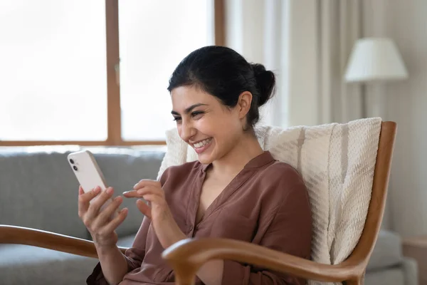 Mujer india joven feliz riendo mirando la pantalla del teléfono inteligente. — Foto de Stock