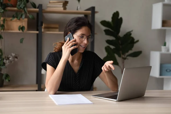Young businesswoman talk by phone doing online work on laptop — Stock Photo, Image