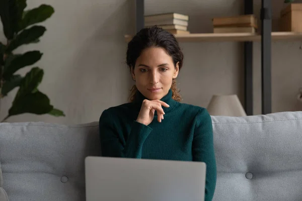 Tankeväckande latinamerikansk dam använda laptop på soffan hemma — Stockfoto