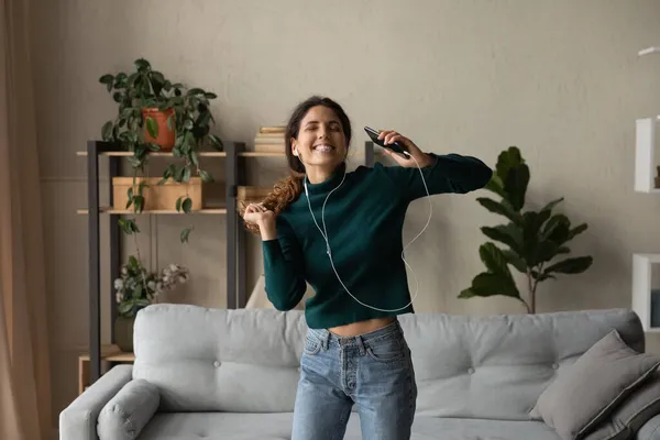 Excited young female jump by music from cellphone in headset — Stock Photo, Image