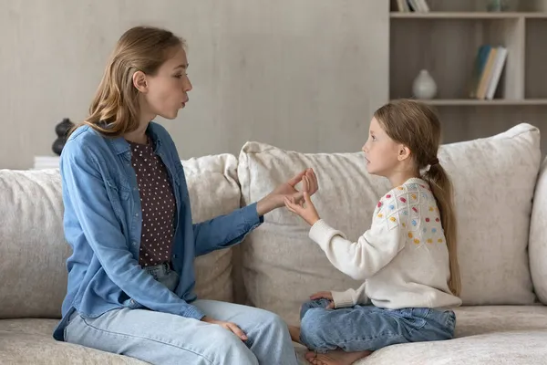 Fokuserad omtänksam ung mor lära liten unge dotter uttala ljud. — Stockfoto